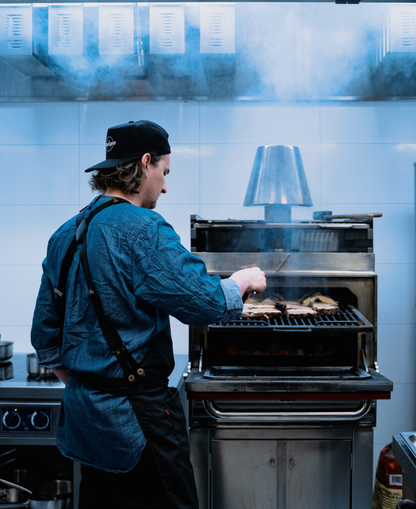 Kjøkkensjef lager mat på grillen.