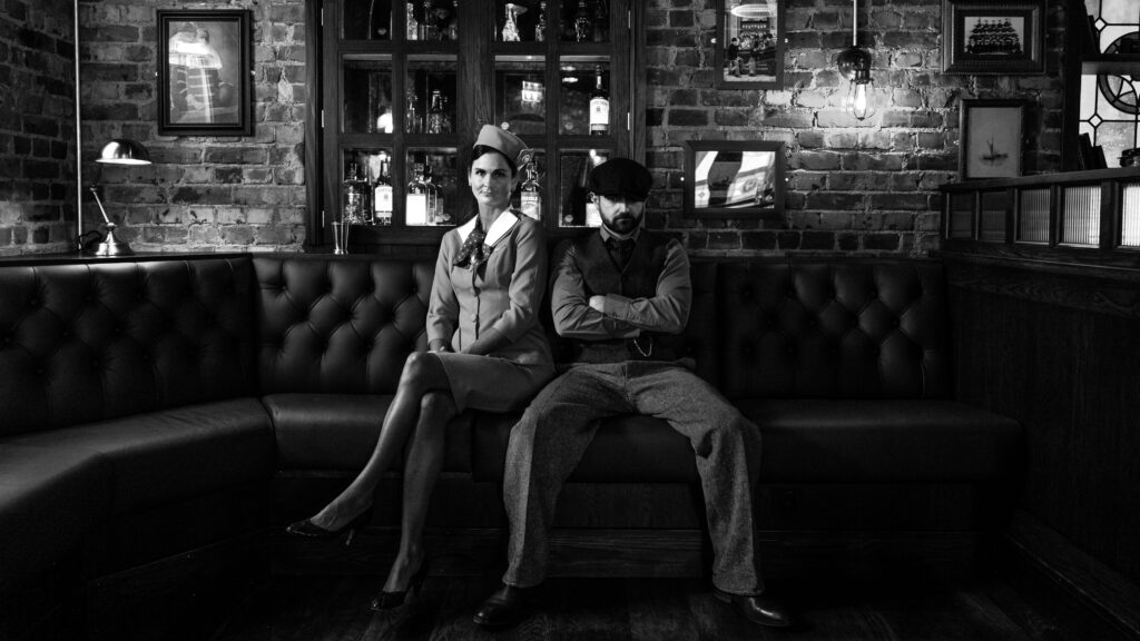 En mann og en kvinne som sitter i en bås i en pub. De ser rett i kameraet.
