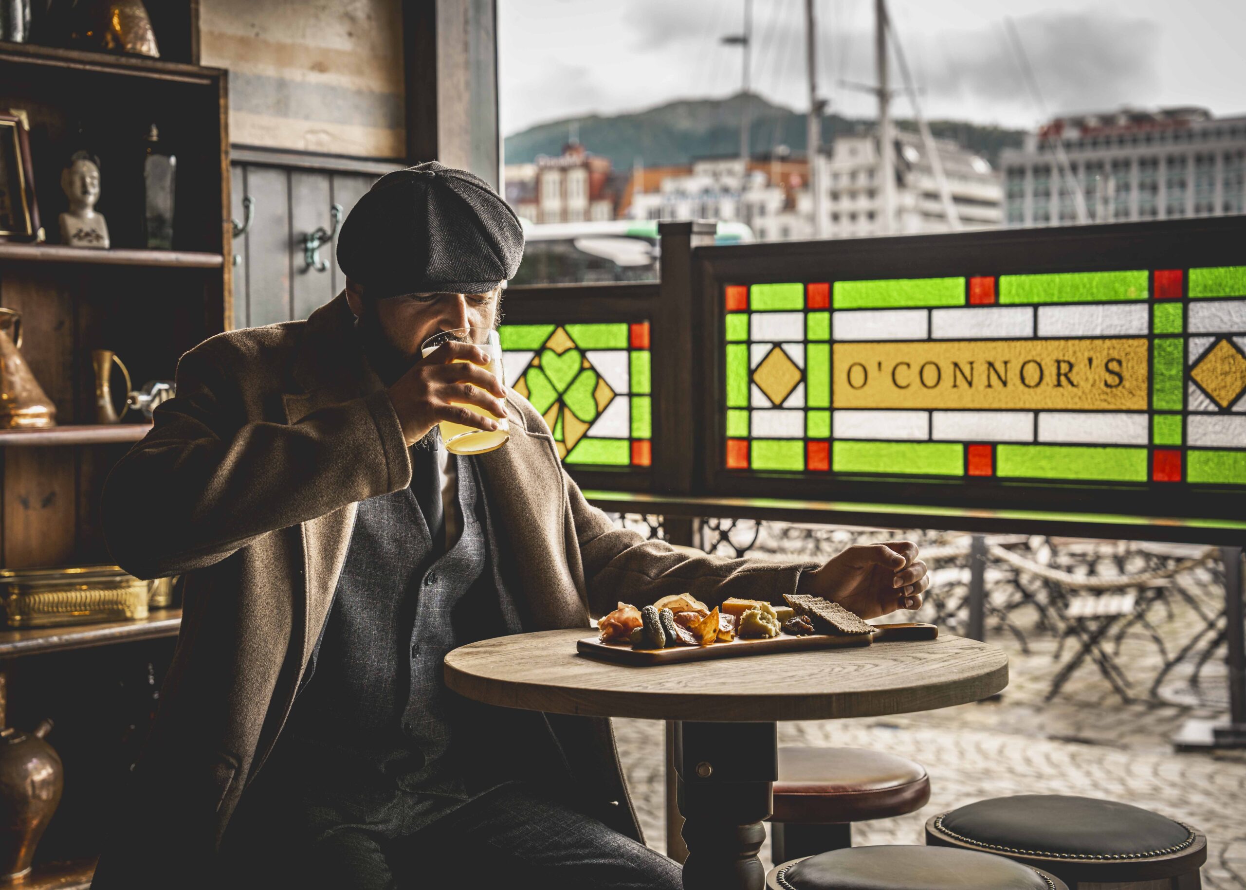 En mann som sitter ved et bord på O'Connor's Bergen med mat på bordet. Han drikker en øl.