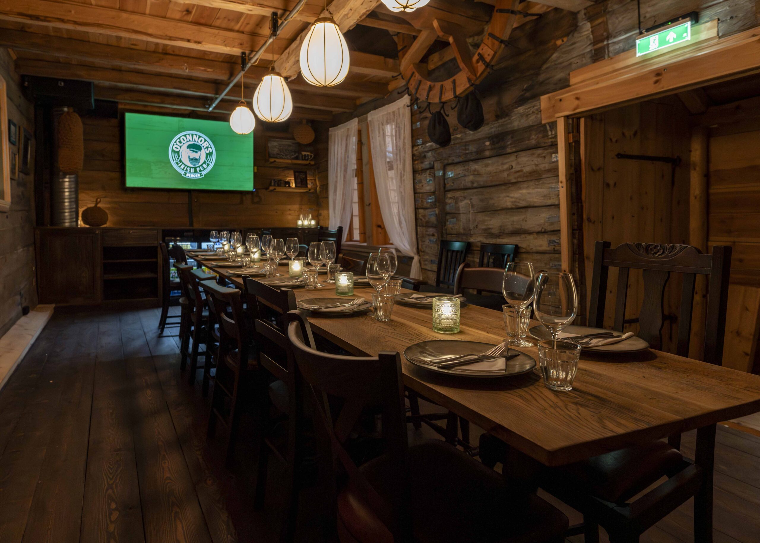 Et langt bord på O'Connor's i Bergen som er dekket til middag foran en TV